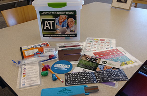 AT Toolkit, a container with a variety of lower tech items, such as high contract keyboard stickers, communication board, ergonomic grips, and more