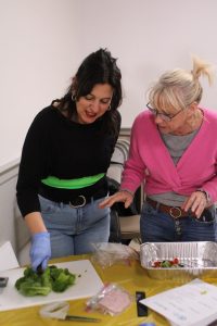 Attendee being instructed on how to cut broccoli with one hand, during the Cooking without Limits training.